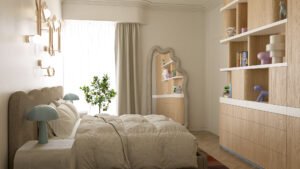 Sypialnia w ciepłych neutralach z tapicerowanym łóżkiem, dekoracyjnym lustrem i rośliną cytrynową.